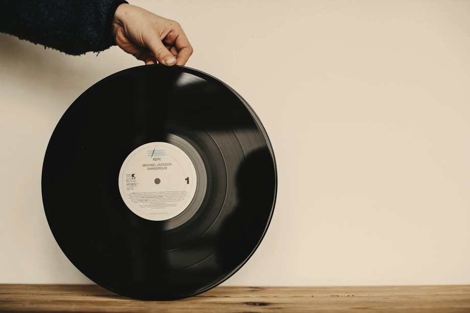Une main ressort un vieux disque vinyle de sa pochette
